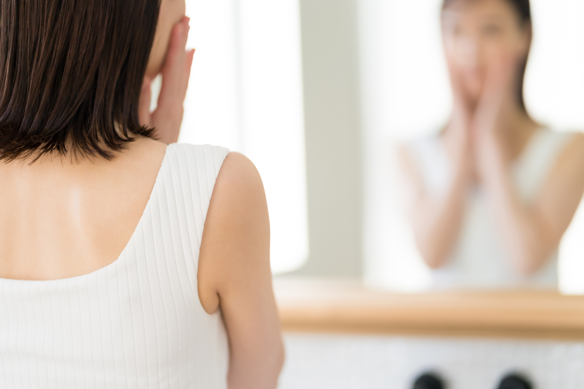 両手で頬に手を当てる女性（ぼかし）