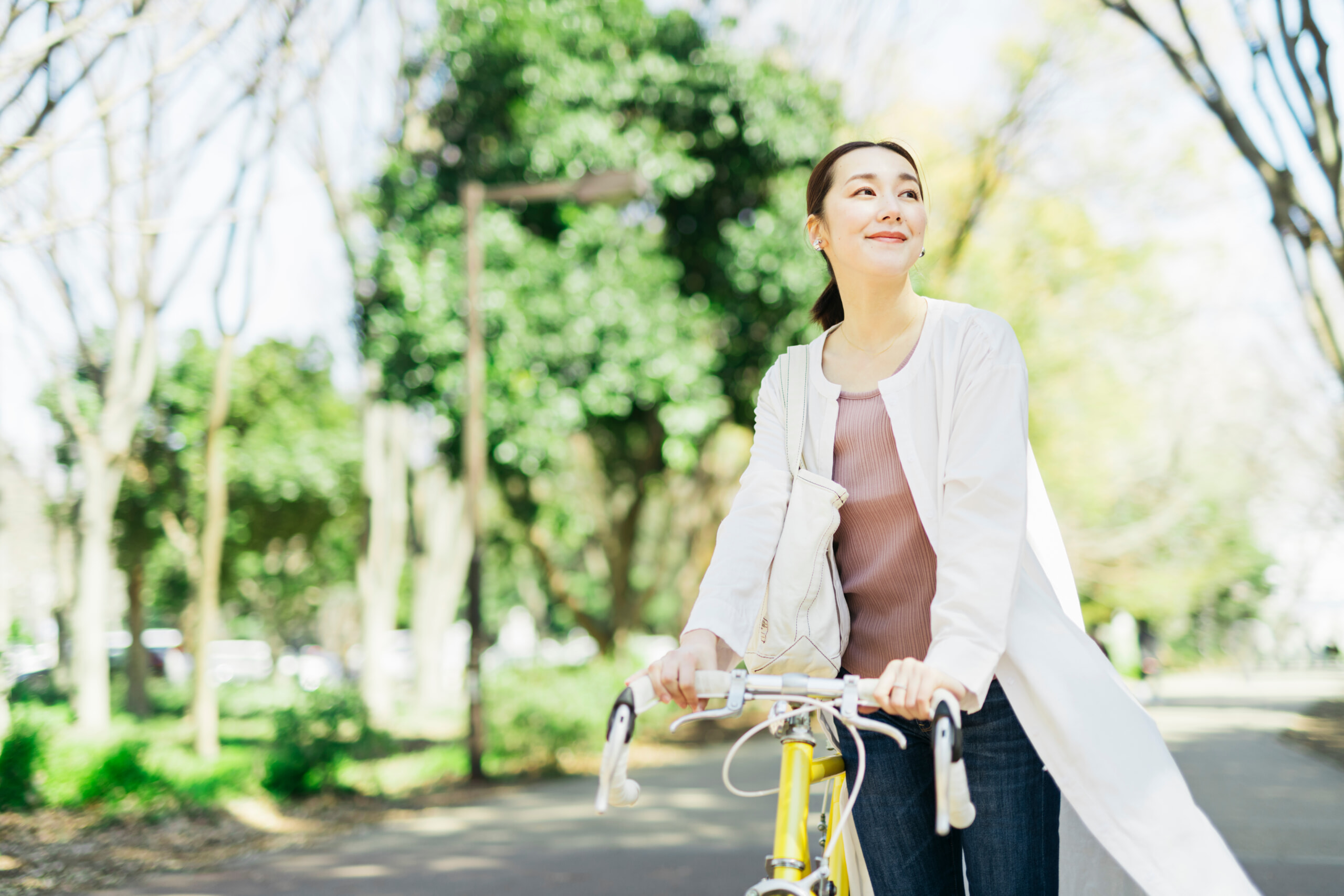 公園で爽やかに自転車を押す女性