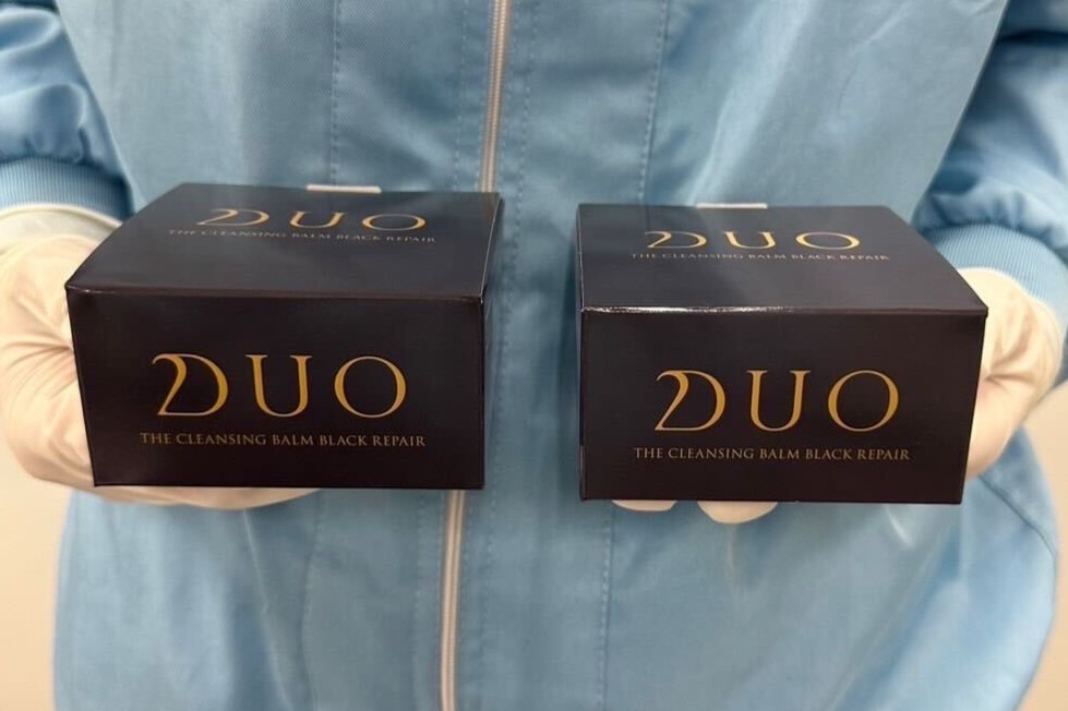 完成したDUO ザ クレンジングバーム ブラックリペアの箱を持つ工場製造スタッフ