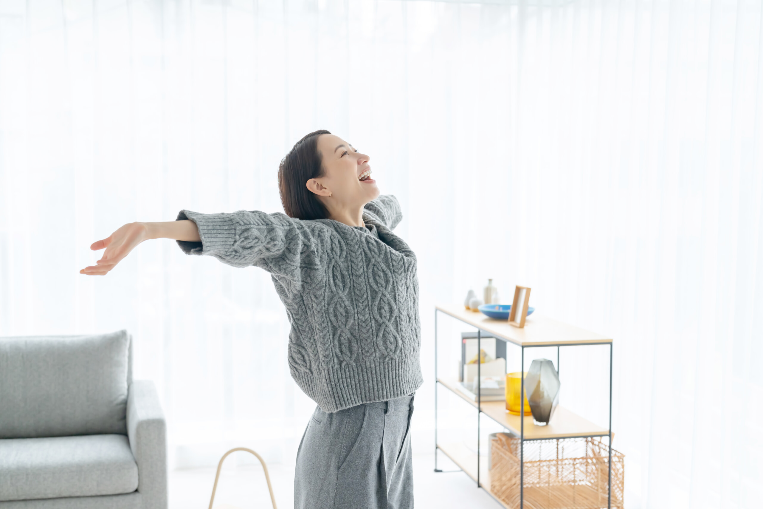 部屋で伸びをするはつらつとした女性