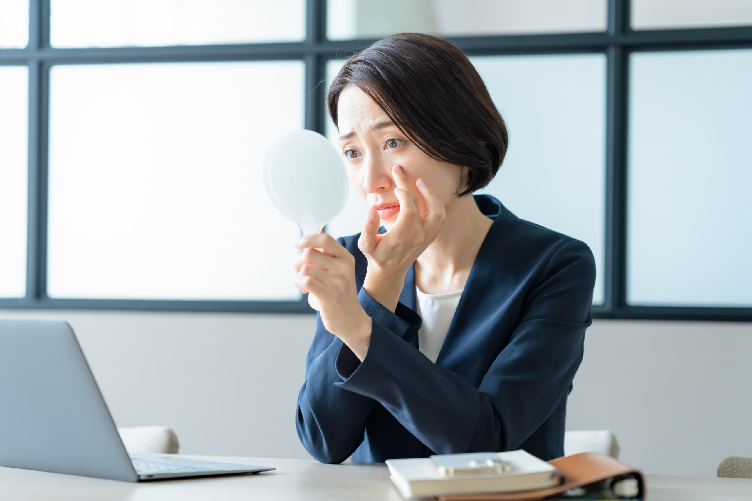 手鏡でメイク崩れを気にする女性