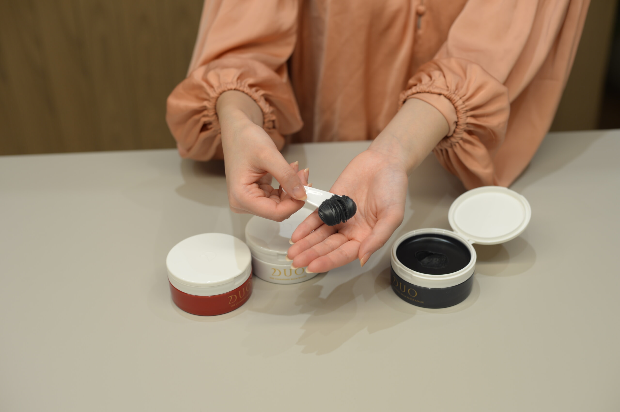 インタビュー風景_DUO ザ クレンジングバーム ブラックリペアのテクスチャーを見せる商品企画開発担当者