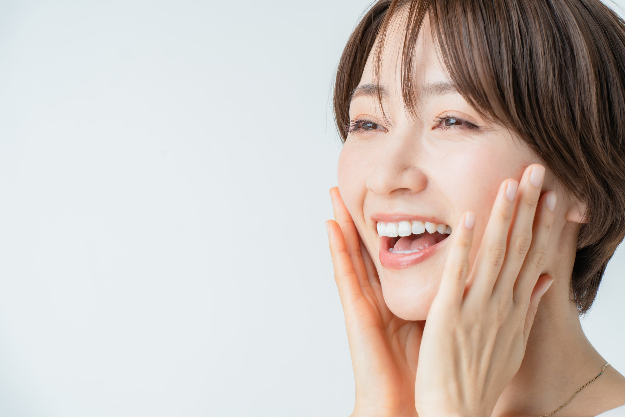 両手を頬に当てて笑顔の女性