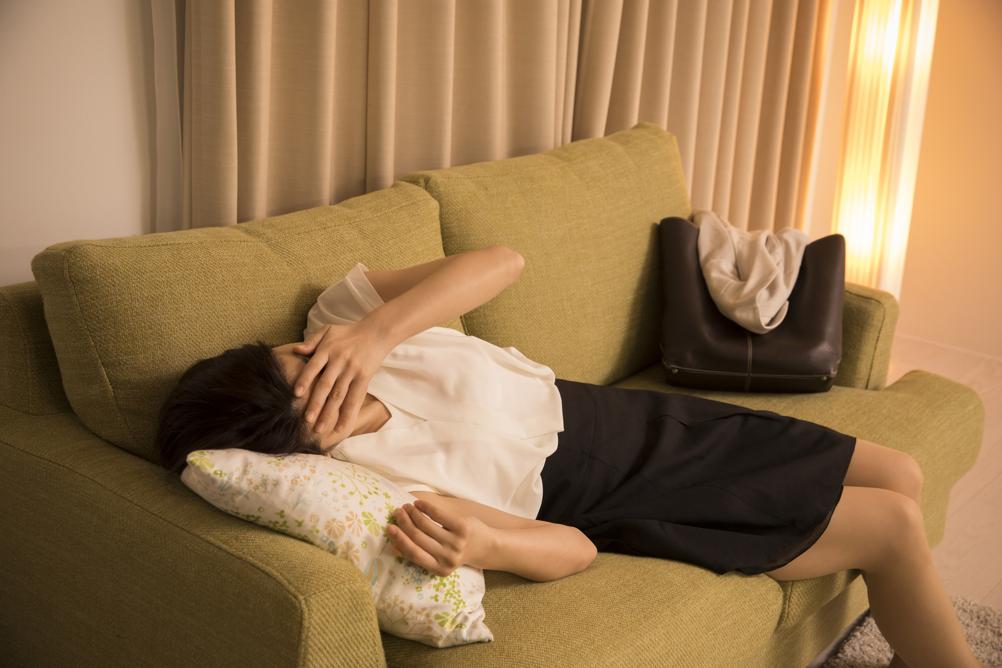帰宅直後にソファで横になる女性