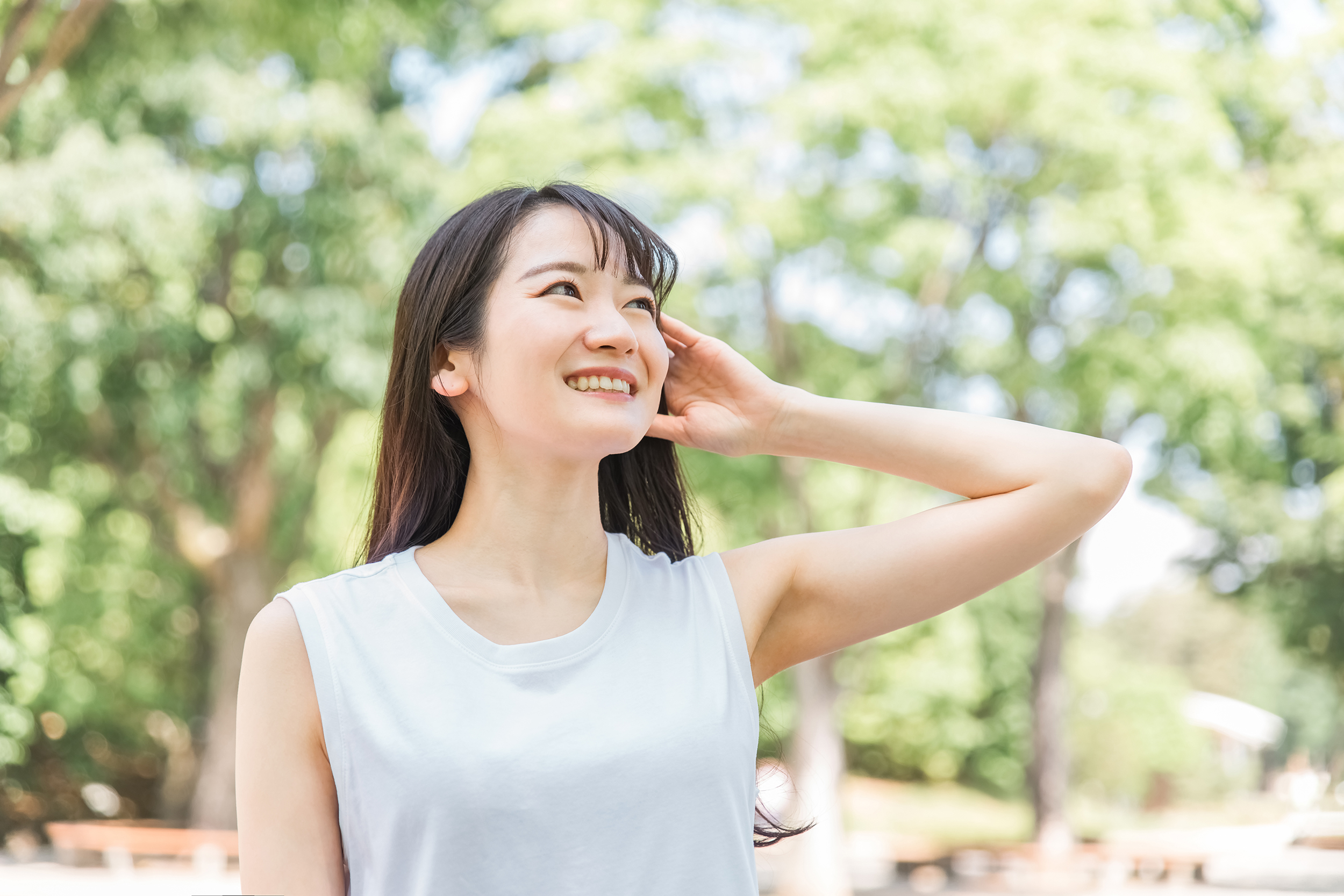 イメージ素材_新緑の中で髪を触る笑顔の日本人女性