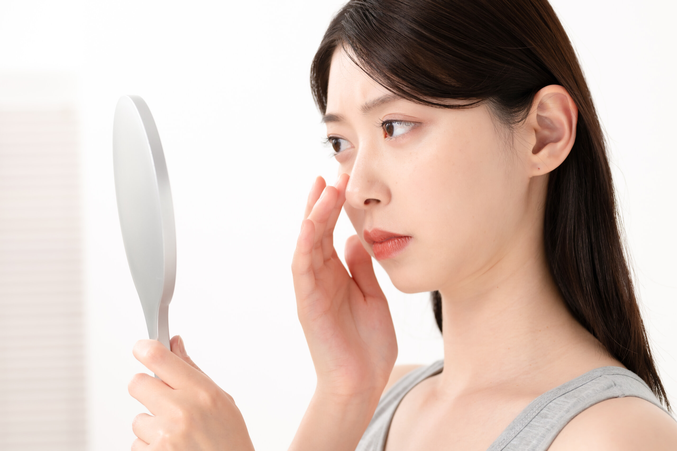 自分の肌をテカリかツヤかチェックしている女性