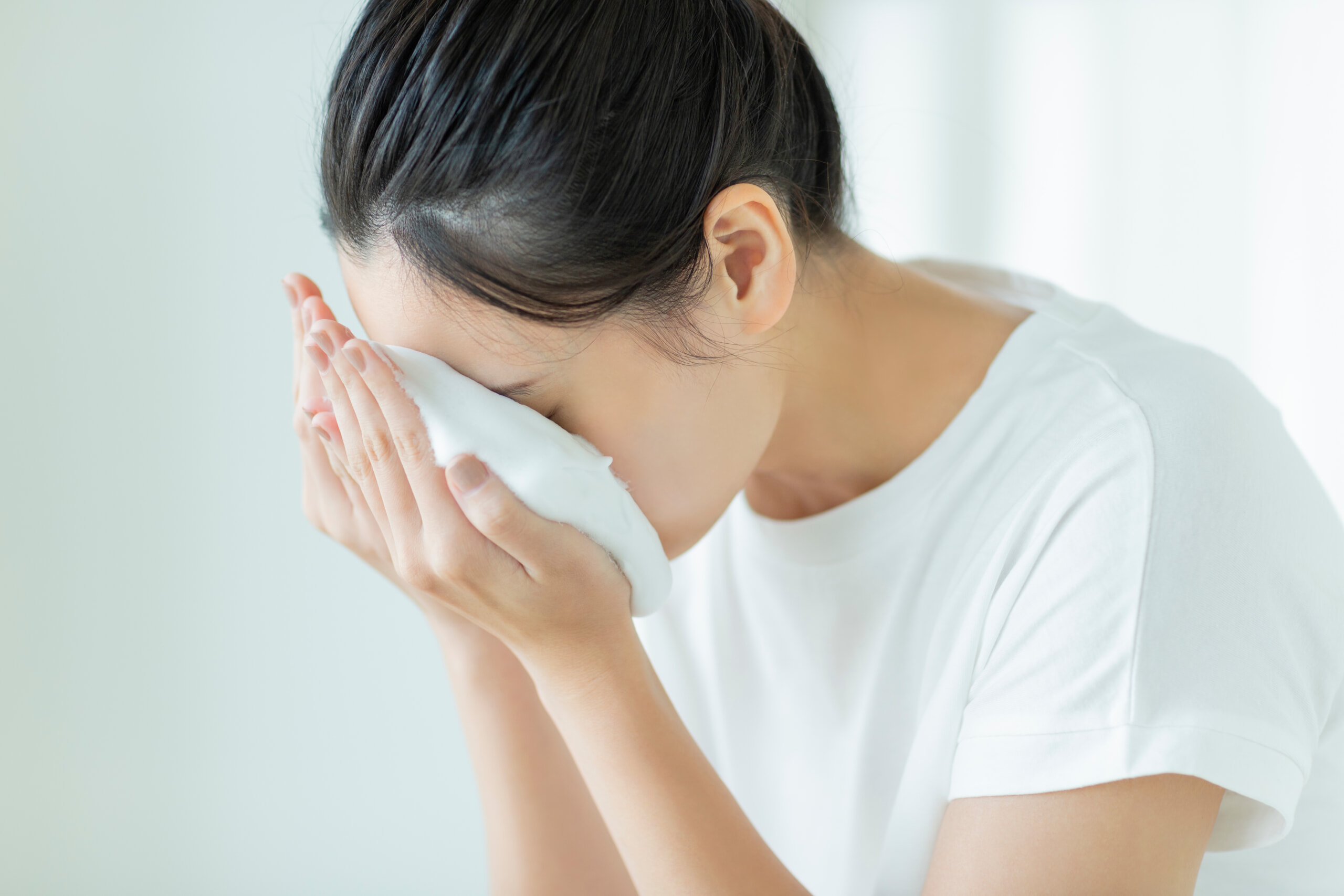 両手にたっぷりの泡を顔につける女性