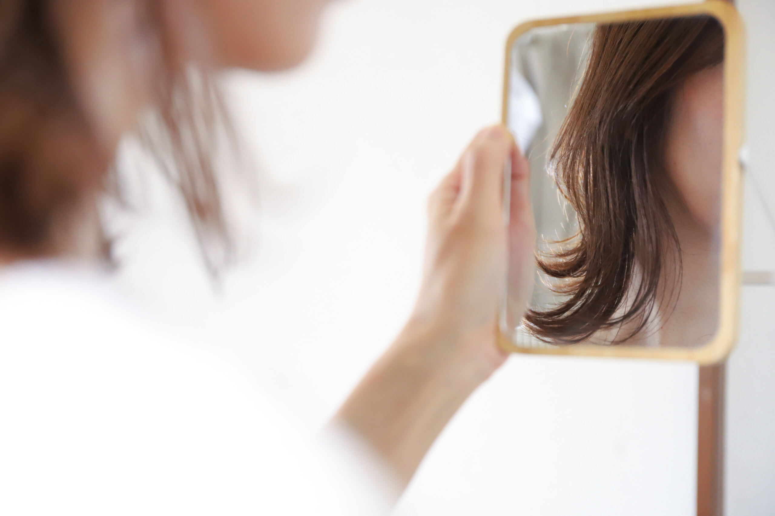 鏡で髪型をチェックする女性