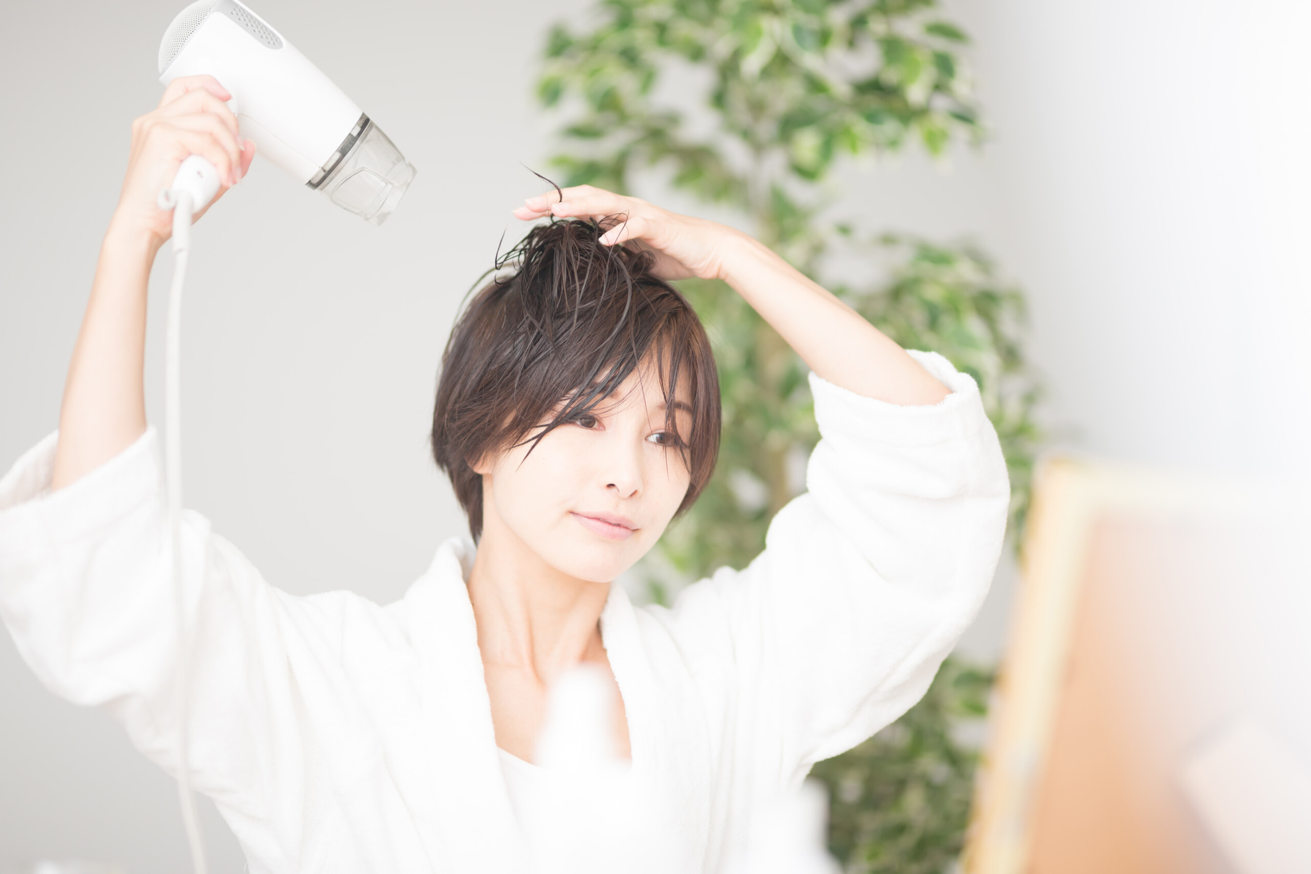ドライヤーで髪を乾かす女性