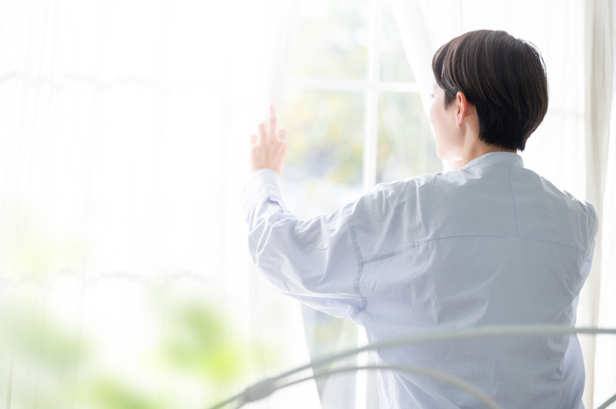 カーテンを開ける女性