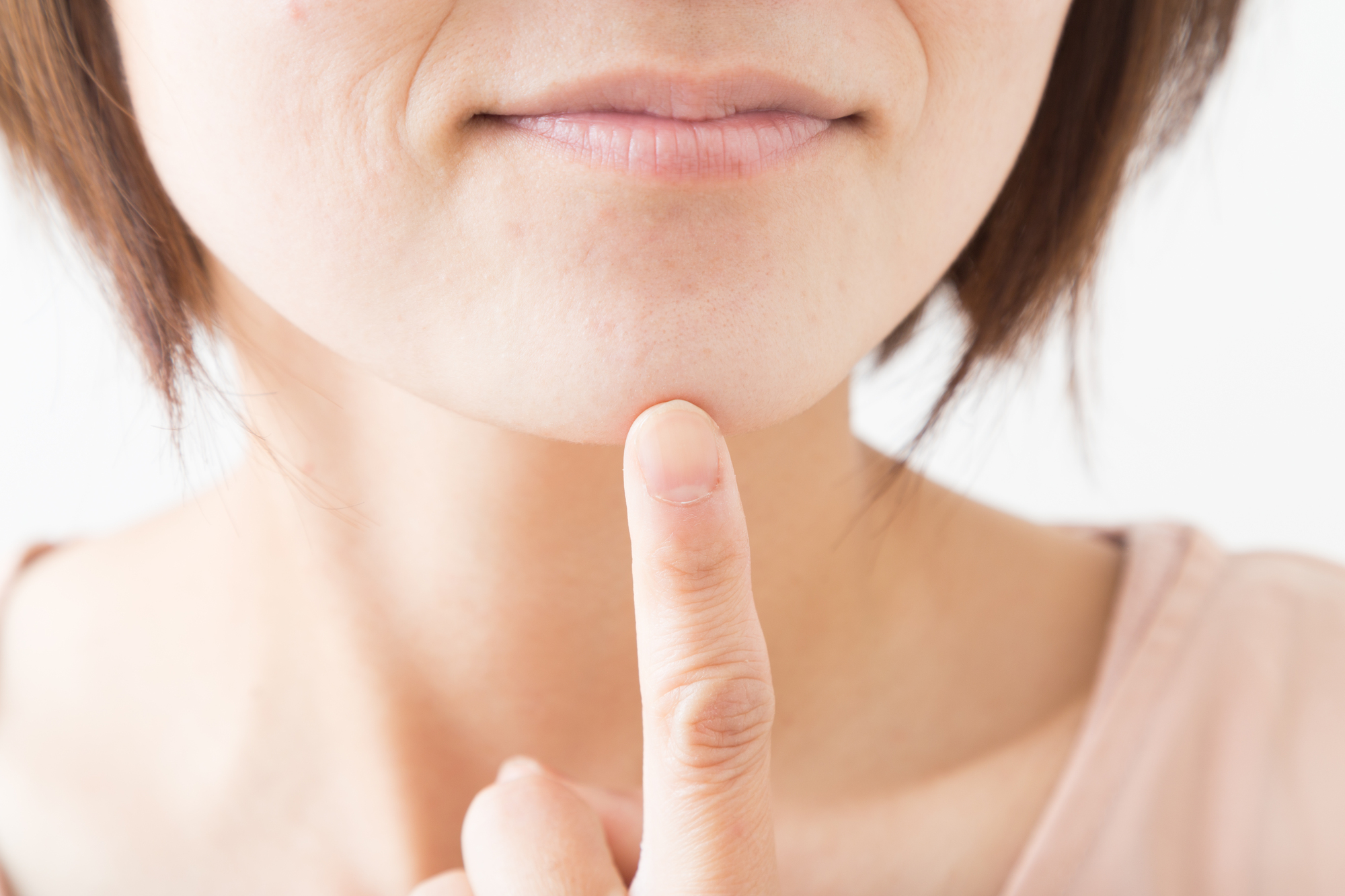あごを指差す女性の半顔