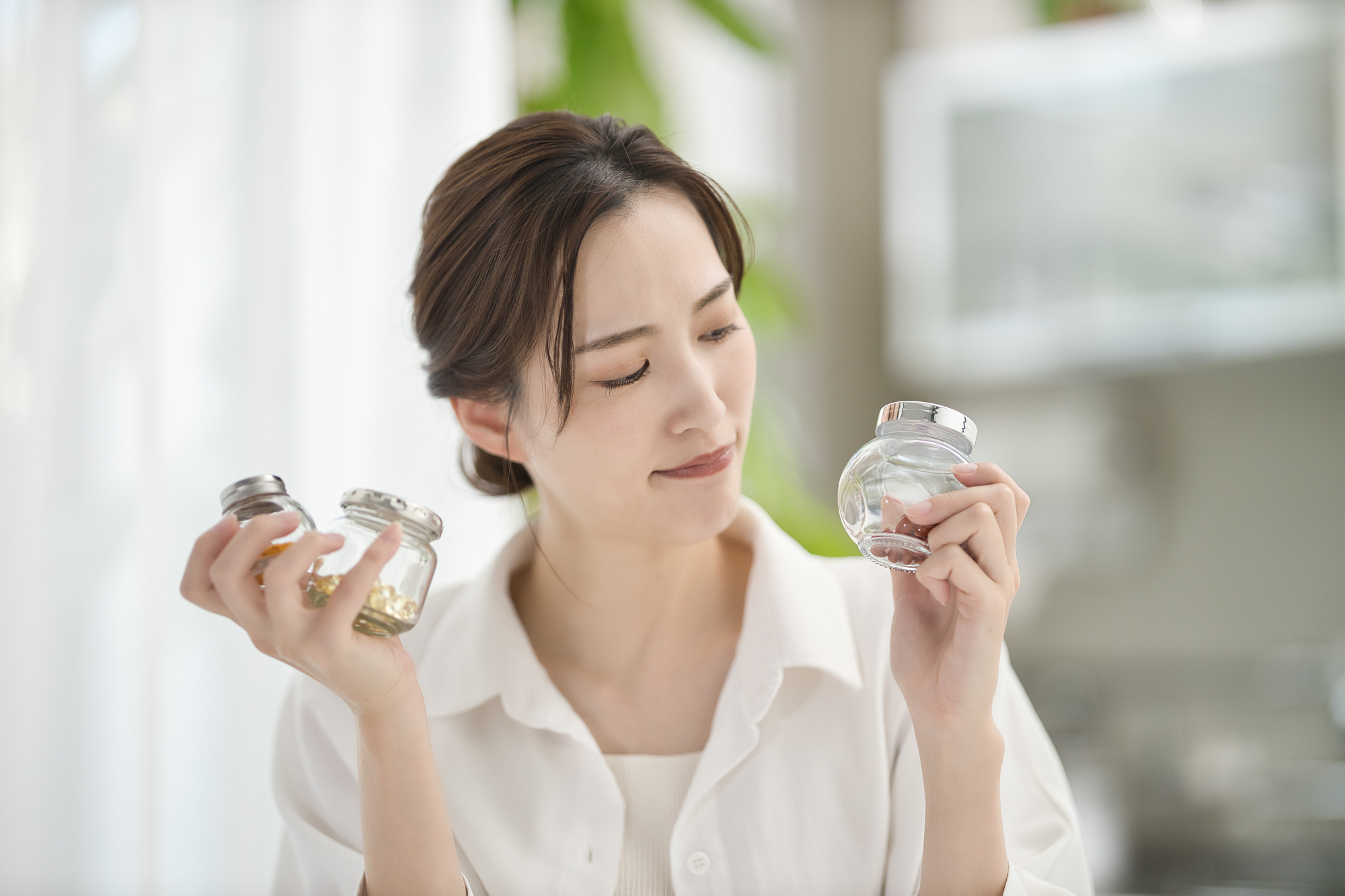 両手にサプリを取り首を傾げる女性