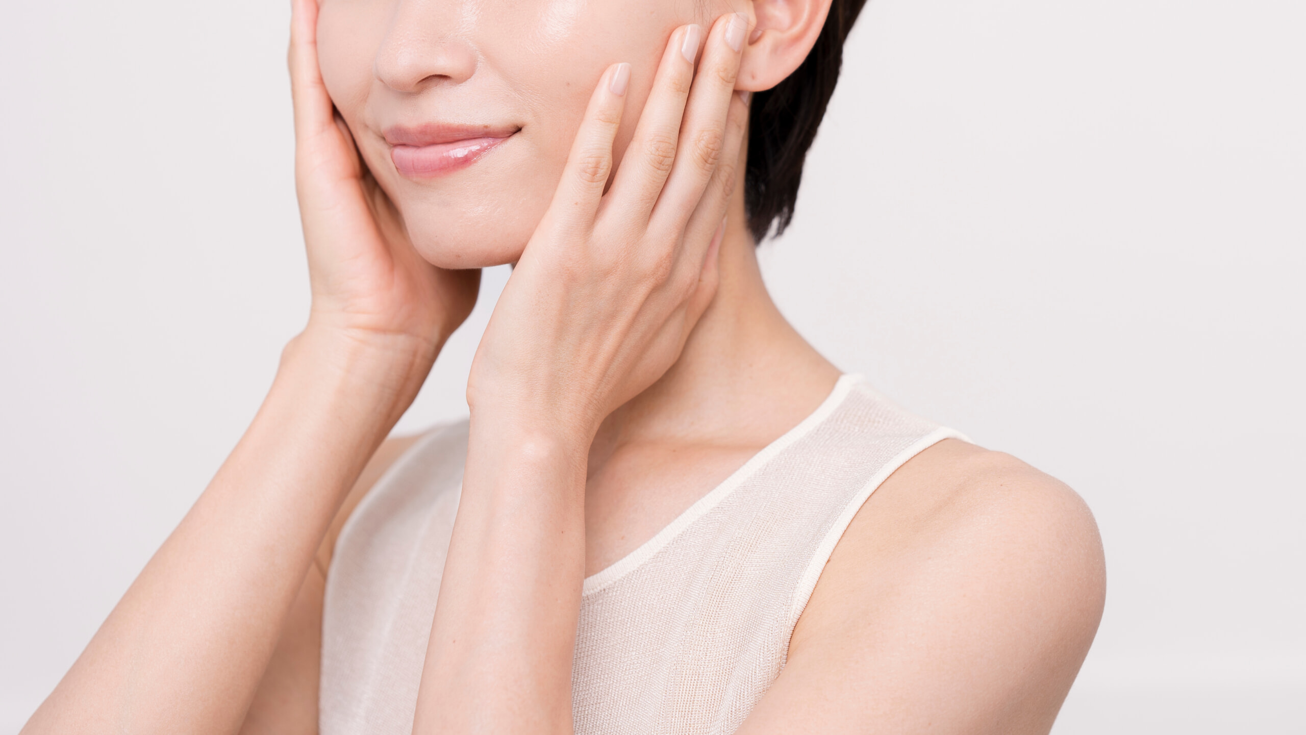 両手を頬にあてる美肌の女性