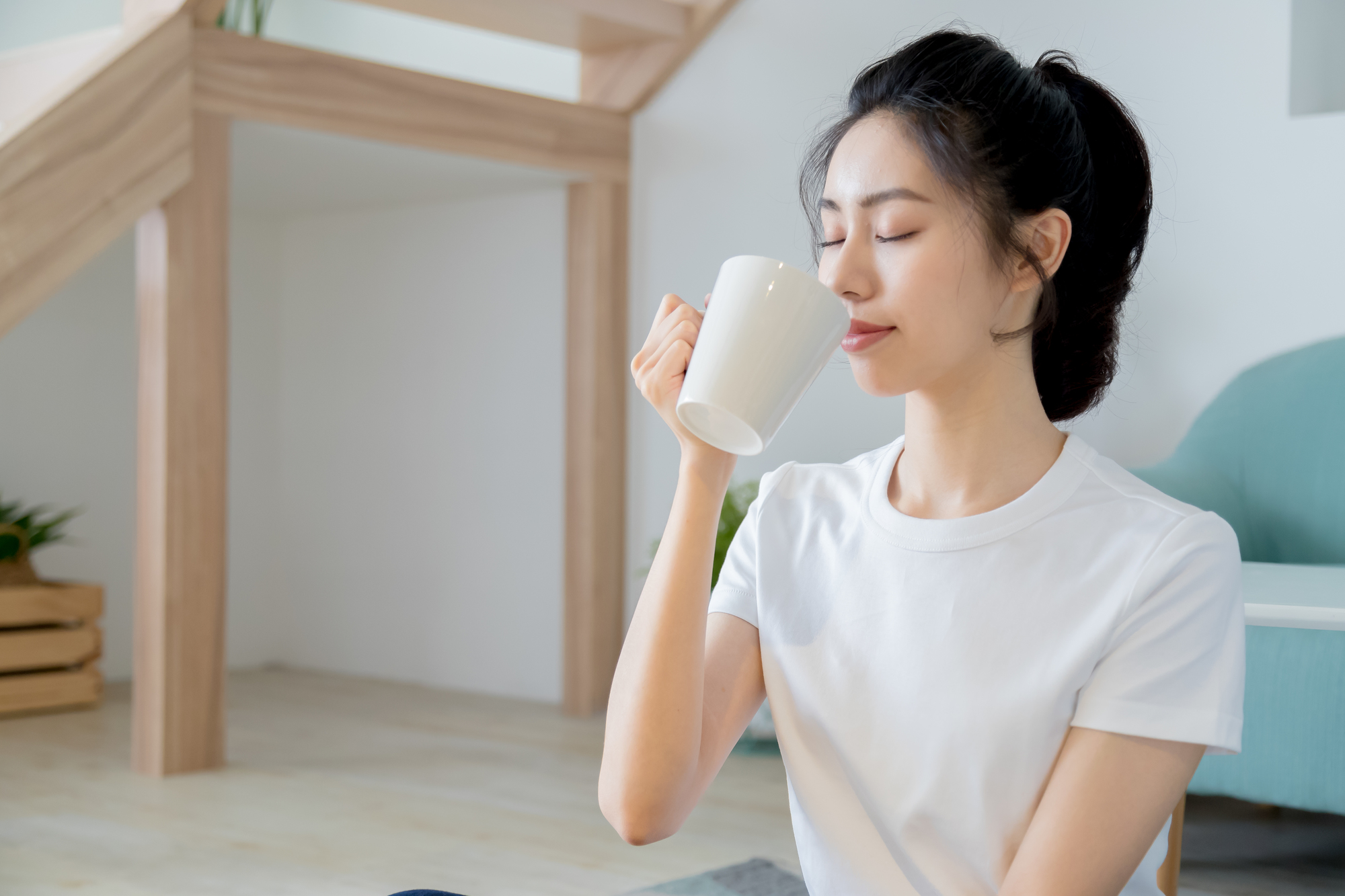 室内であたたかい飲み物を飲む女性