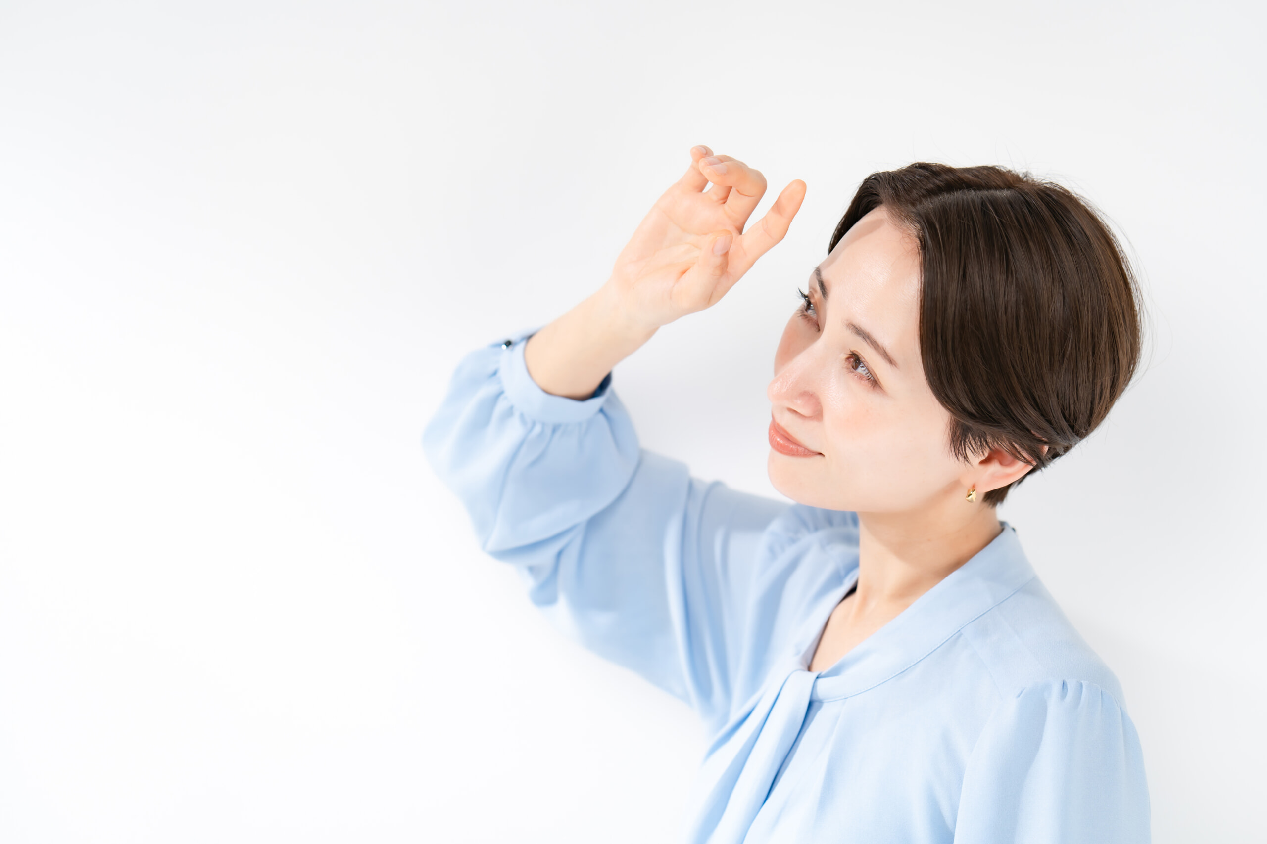 光を手で遮る女性