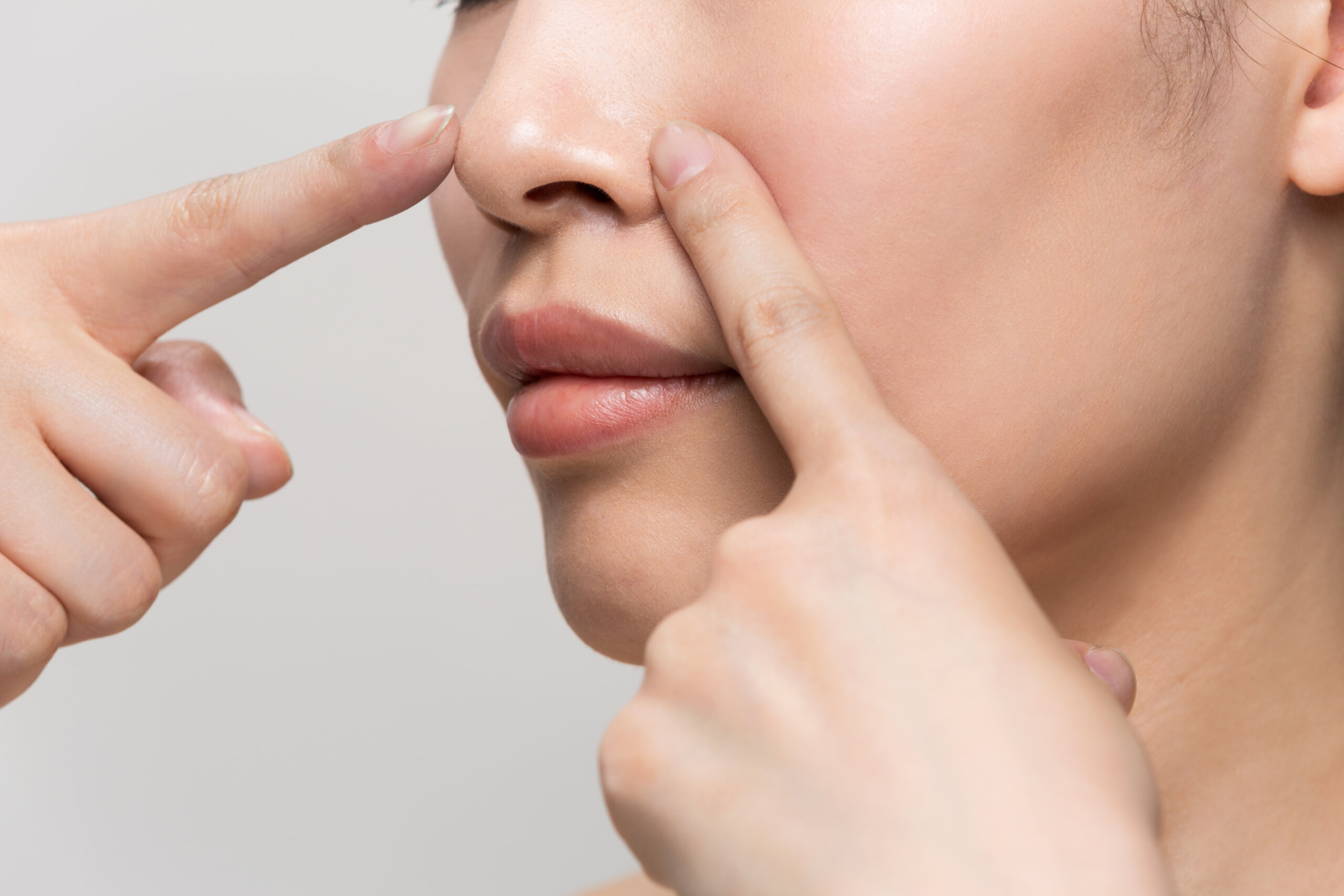 鼻を指さす女性