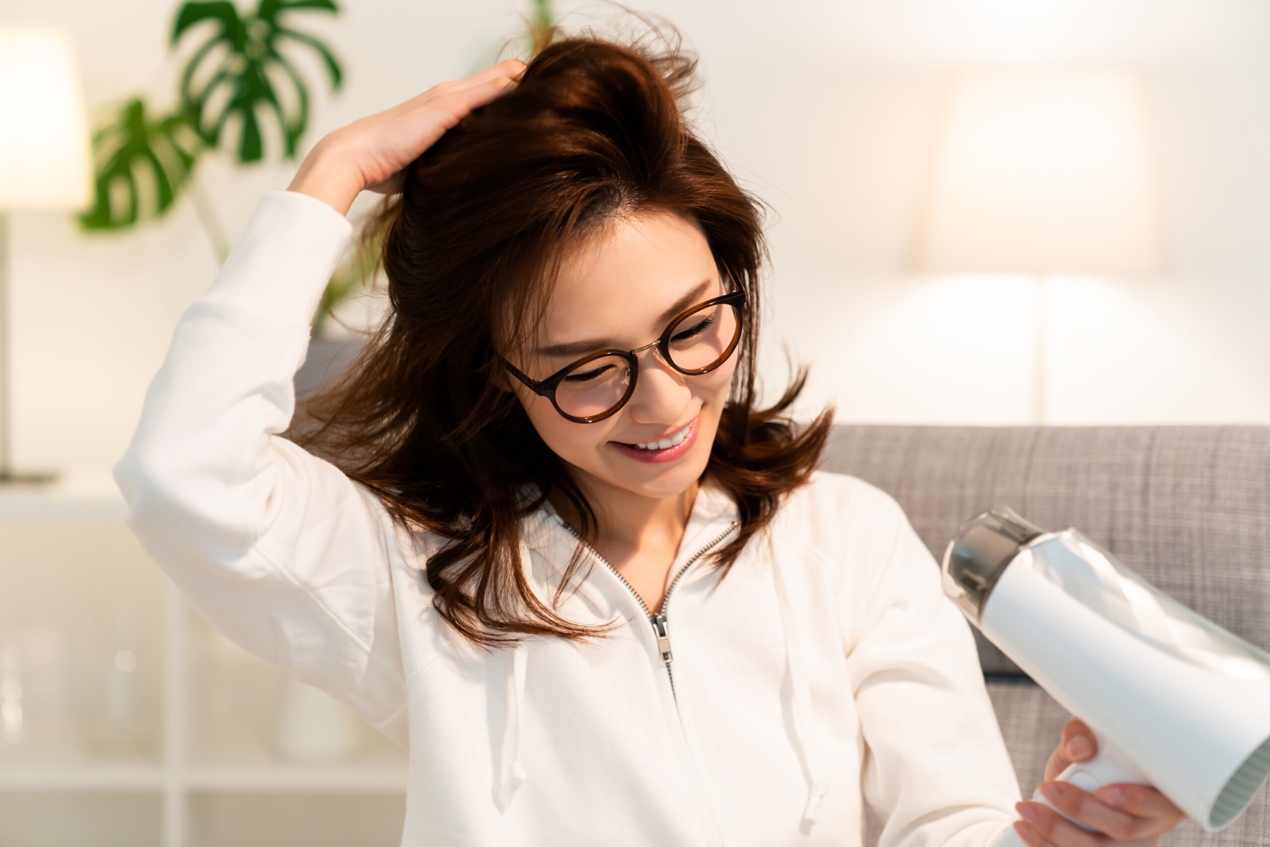 ドライヤーで髪をブローする女性