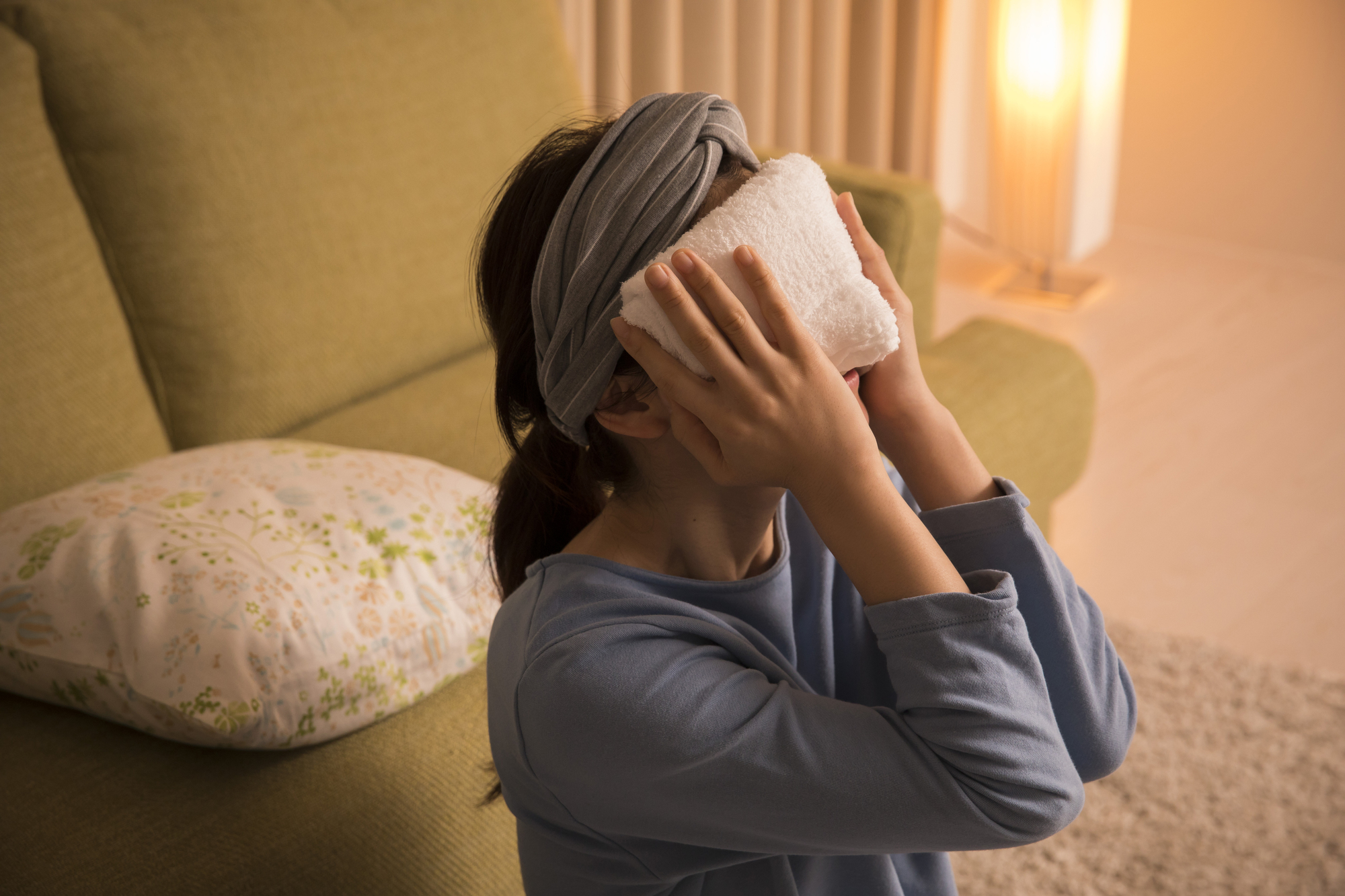 蒸しタオルで顔をあたためる女性