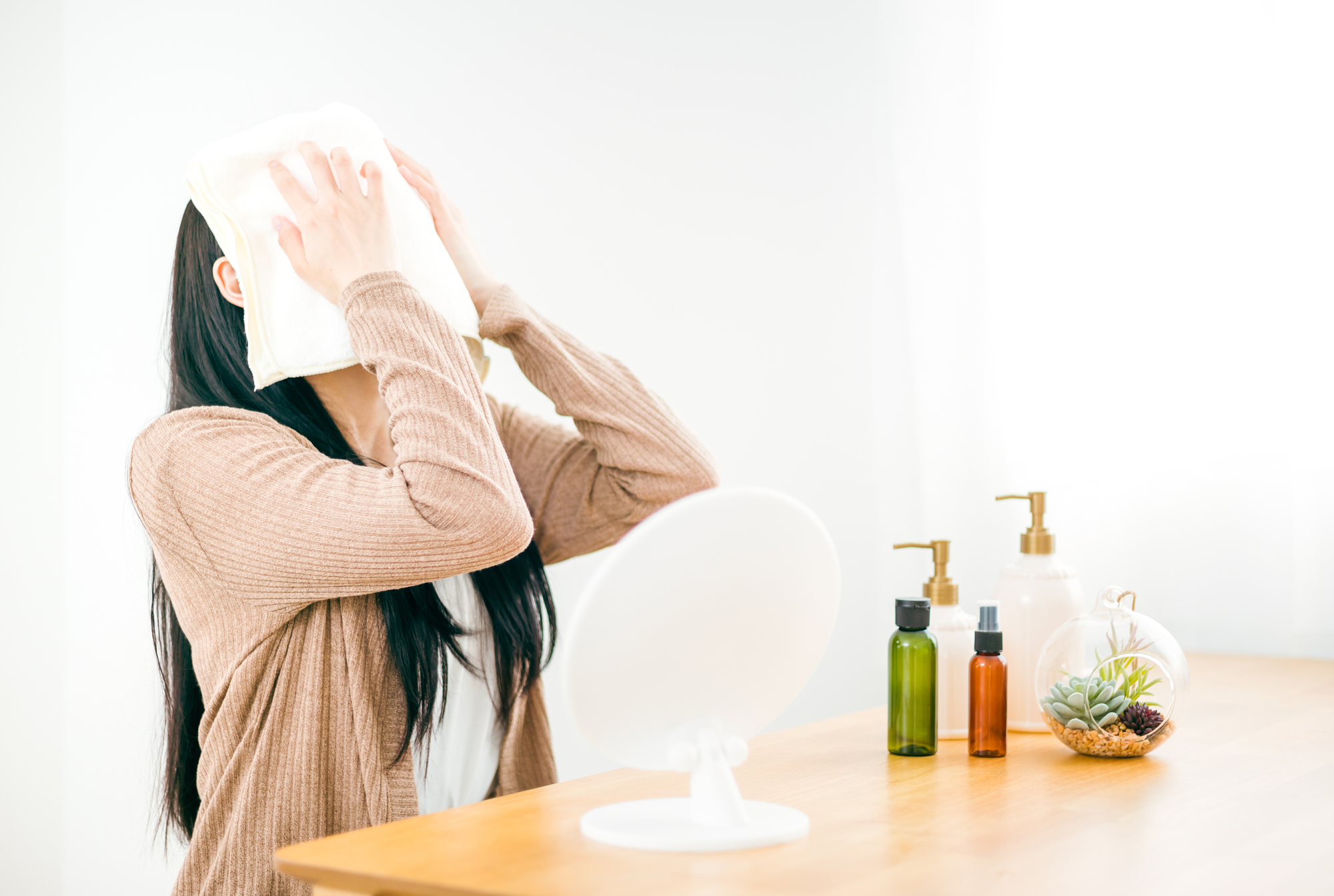 蒸しタオルで顔をあたためる女性