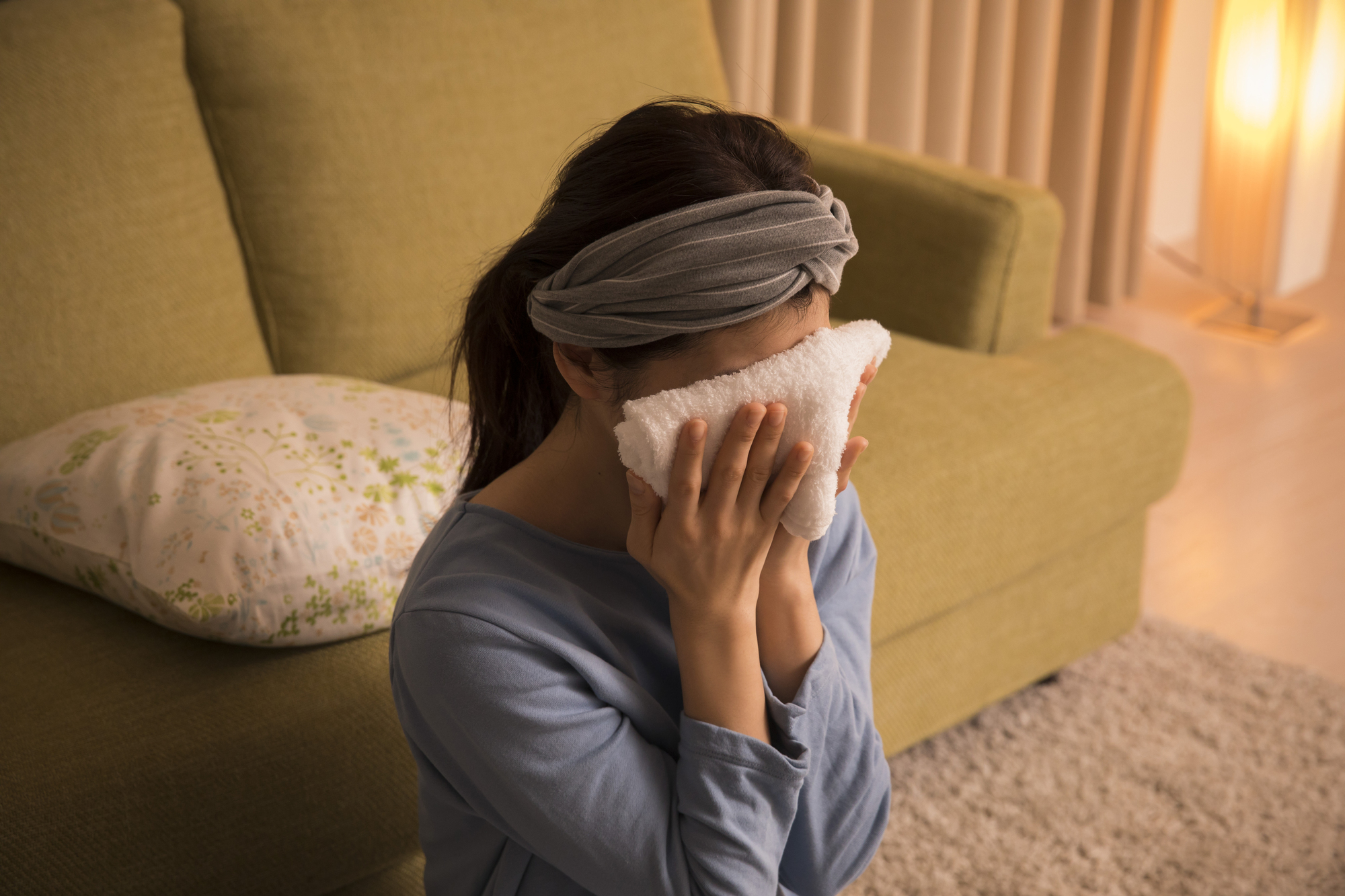 タオルを顔にあてる女性